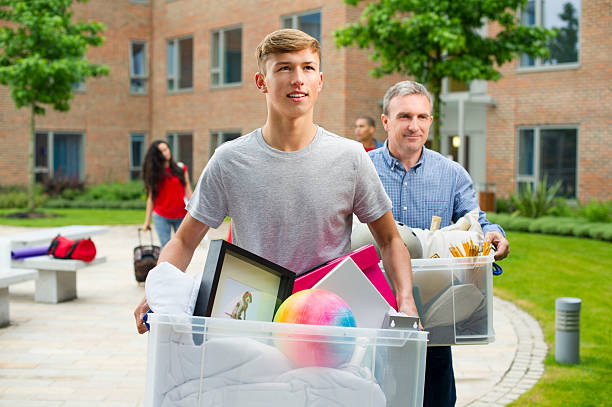 College students carrying plastic storage bins out of a dorm at move-out